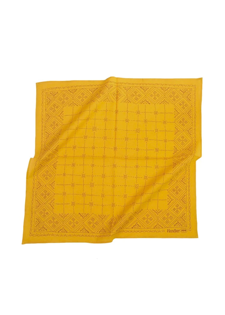 Yellow bandana with a geometric pattern laying on a white background